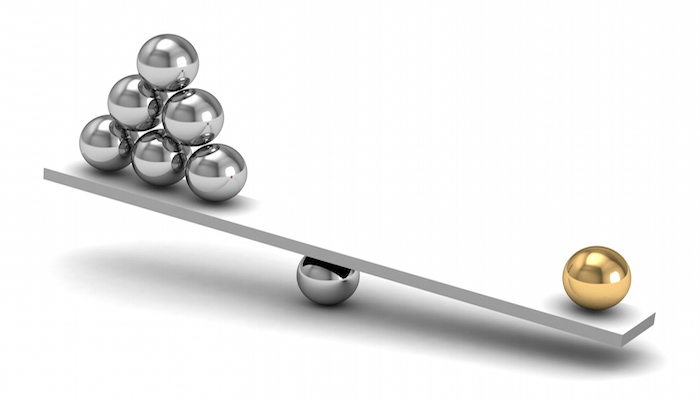 image of scale with 6 silver balls on one side, one gold ball on the other is outweighing the silver.